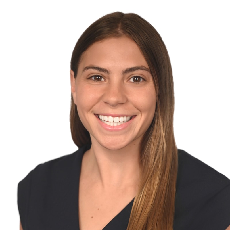 Head-and-shoulders portrait of a smiling woman with long brown hair, wearing a dark top against a white background.